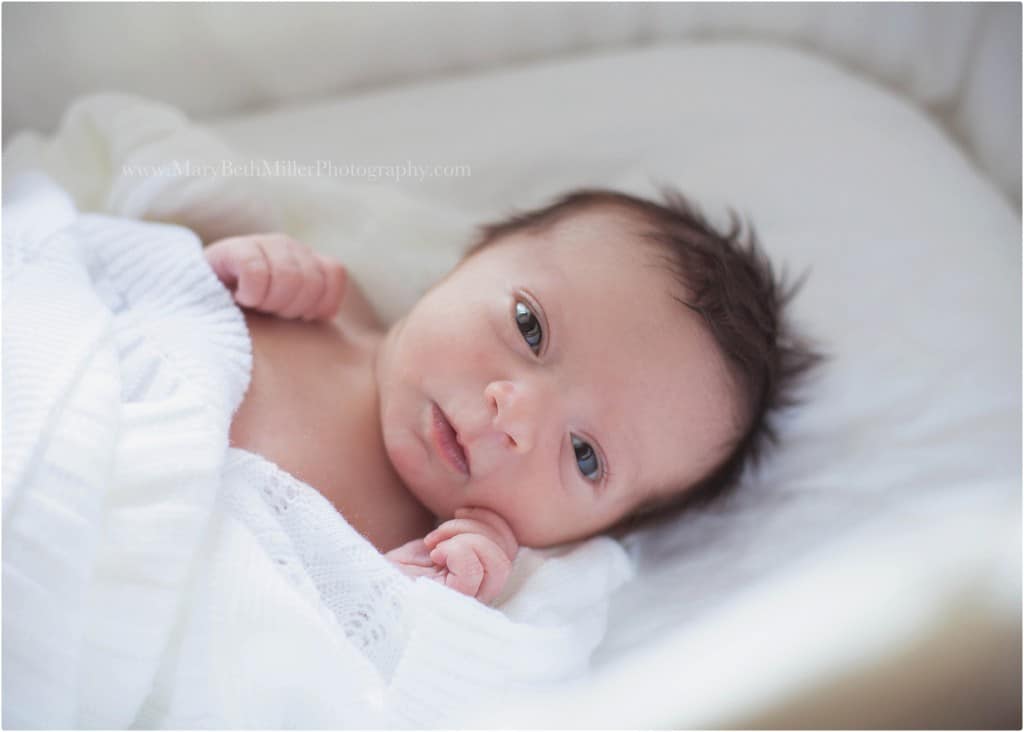 Youngstown ohio newborn photographer newborn baby with a lot of dark hair awake with bright clear eyes swaddled and white blanket