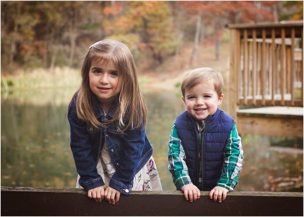 brother and sister smiling on a bench at Townsend park in murrysville with fall leaves and foliage in the background