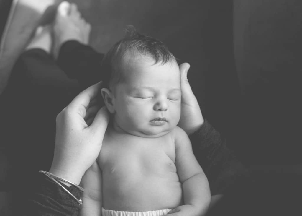 newborn baby sleeping in the hands of mom in black and white
