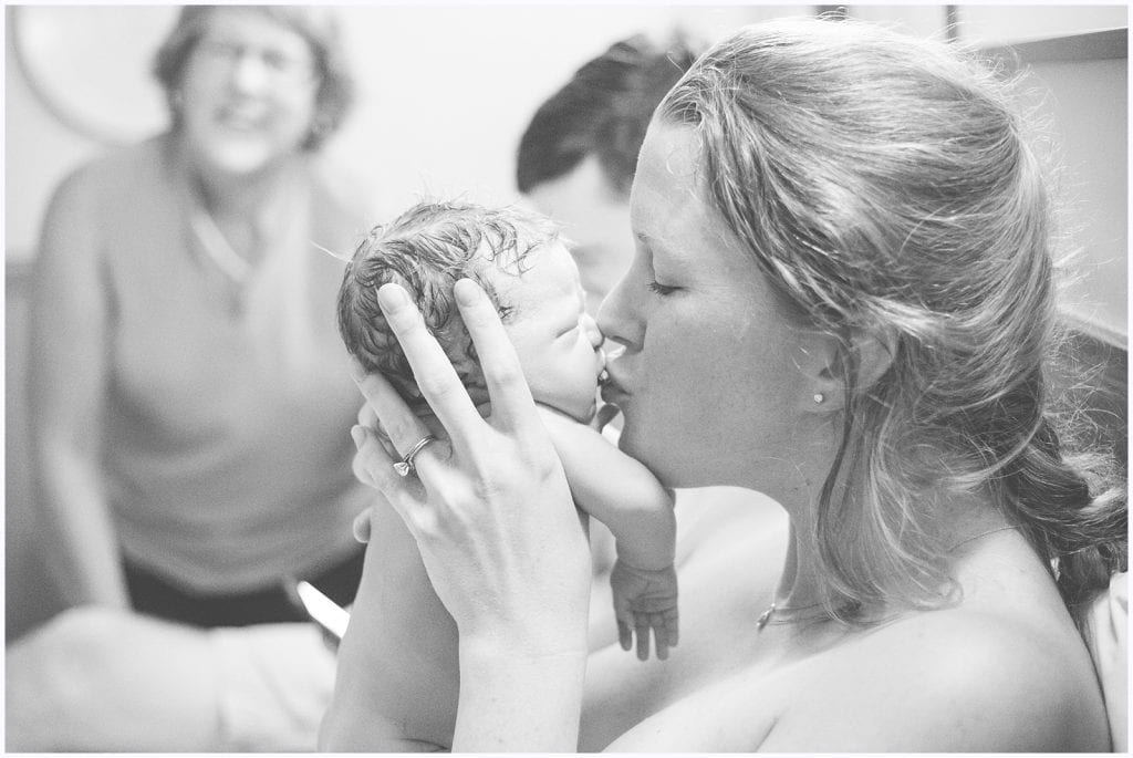 Mother with a messy French braid kissing her newly born baby girl on the lips at the Midwife center in Pittsburgh