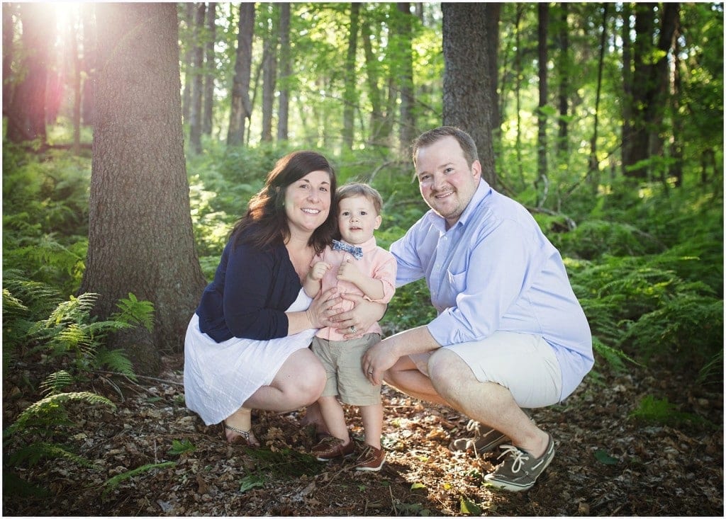 Mother and father and father son crouching down in the woods with ferns and trees and sunlight behind them pittsburgh portrait photographer mary beth miller photography family photo session at Peters lake park Washington Canonsburg