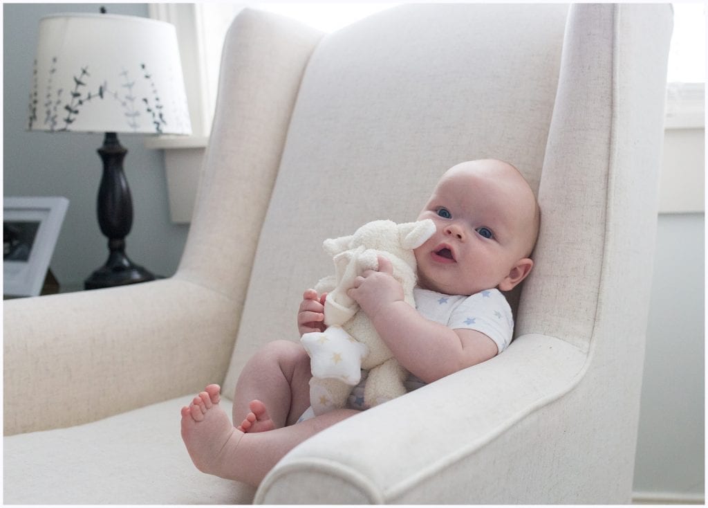 baby on chair with teddy bear in the nursery