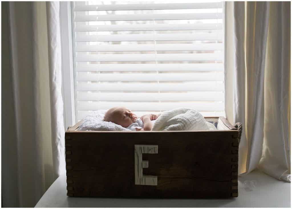 newborn baby girl in crate by window light