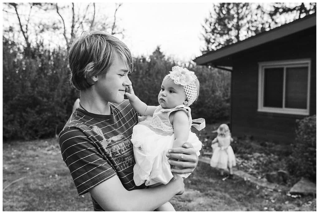 black and white photo of older boy holding baby