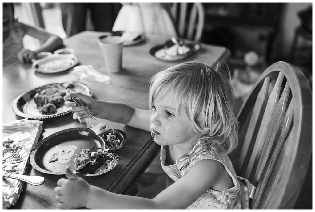 black and white photo of toddler girl eating messy face