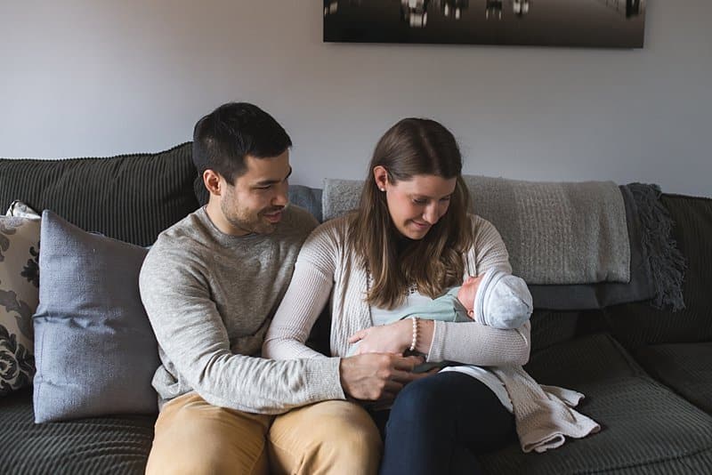 mom and dad with newborn baby on couch at home in pittsburgh