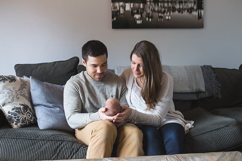mom and dad with newborn baby on couch at home in pittsburgh