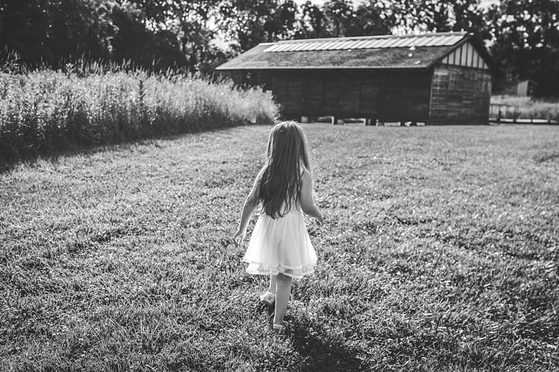 girl walking through meadow pittsburgh field with barn in black and white