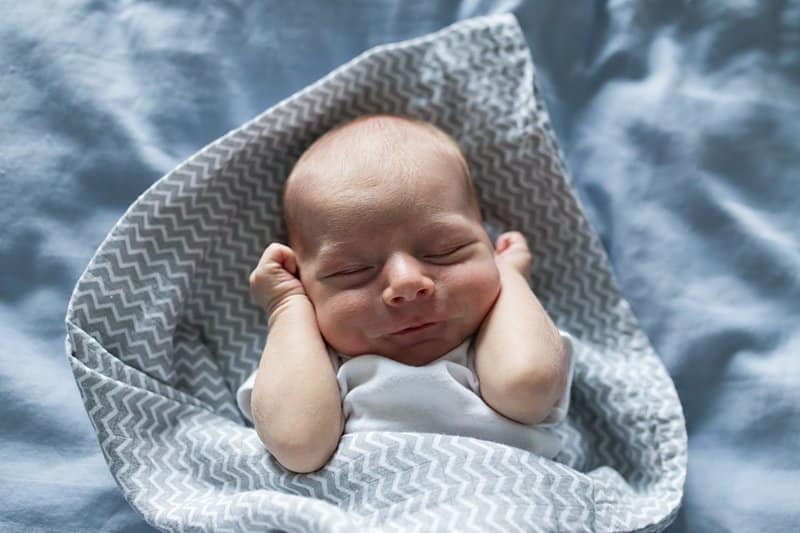 newborn baby on bed lifestyle photo session 