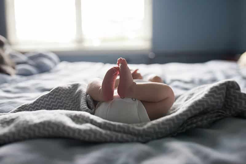 newborn baby feet and legs on bed lifestyle photo session 