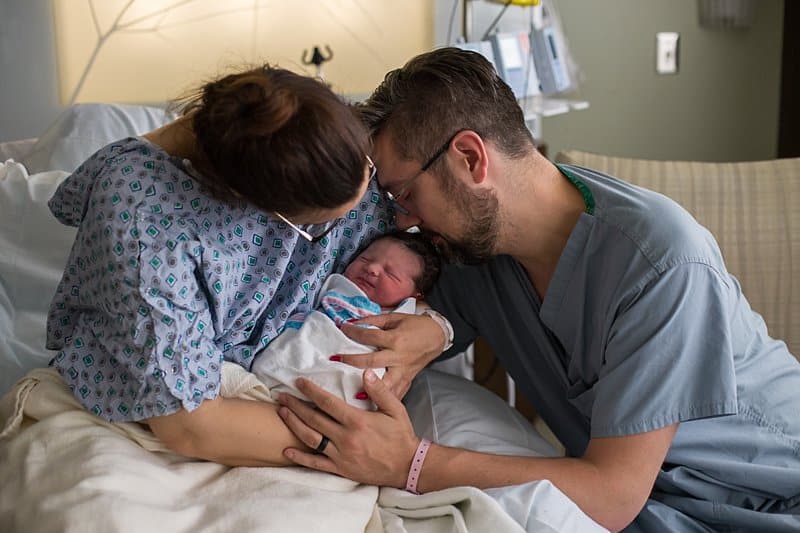 newborn with dad and mom in hospital bed birth session in pittsburgh