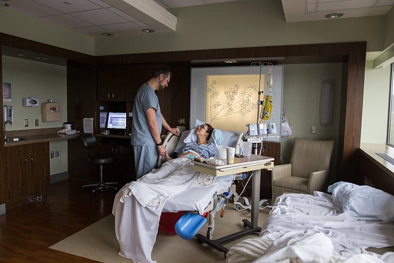 dad supporting mom in hospital bed birth session in pittsburgh
