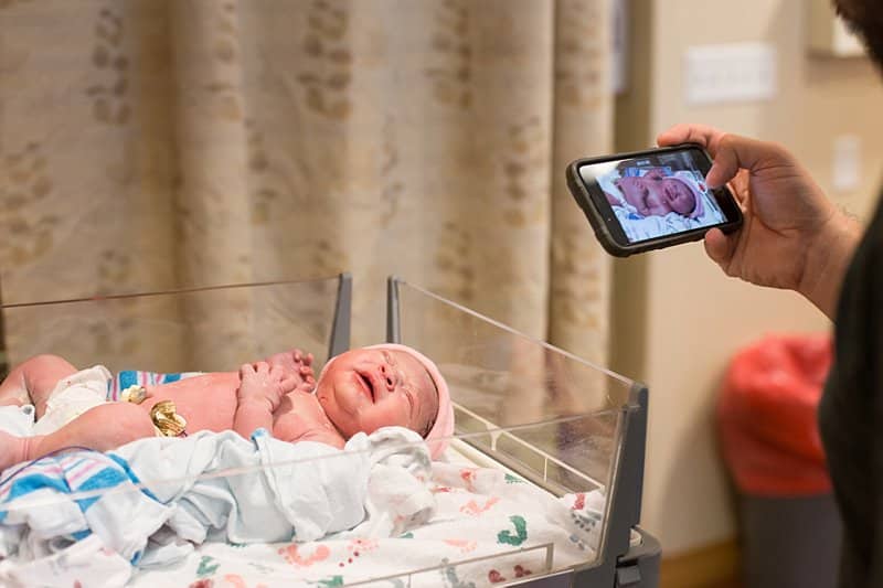 dad photographing baby hand during newborn exam at magee womens hospital pittsburgh