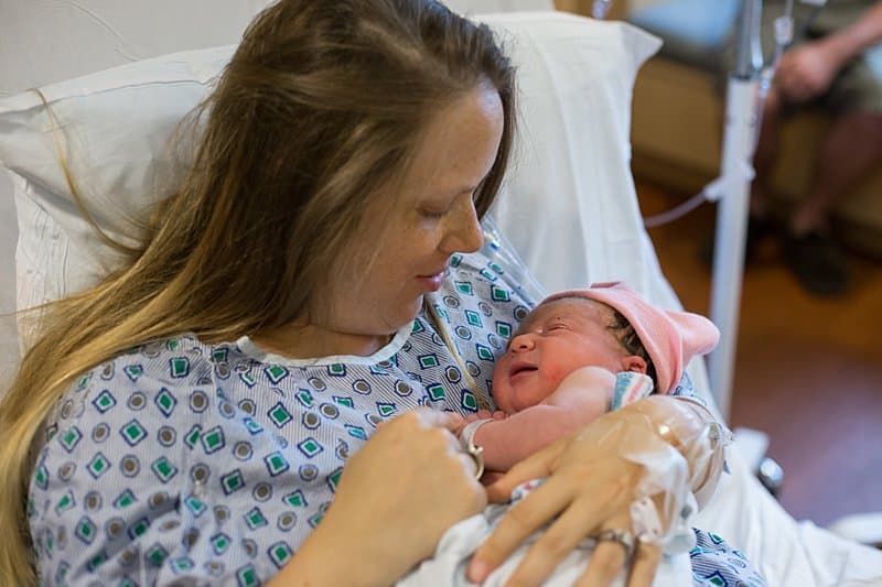 mom holding newborn baby girl in bed at magee womens hospital pittsburgh