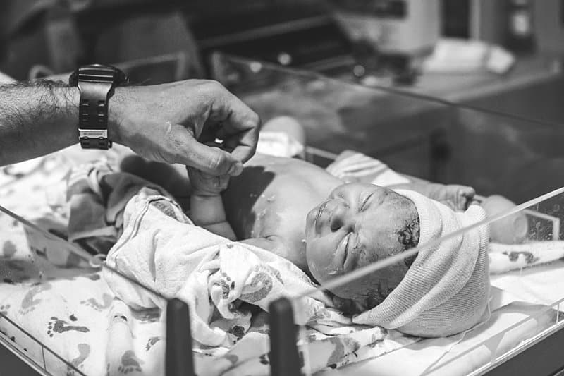 dad holding baby hand during newborn exam at magee womens hospital pittsburgh