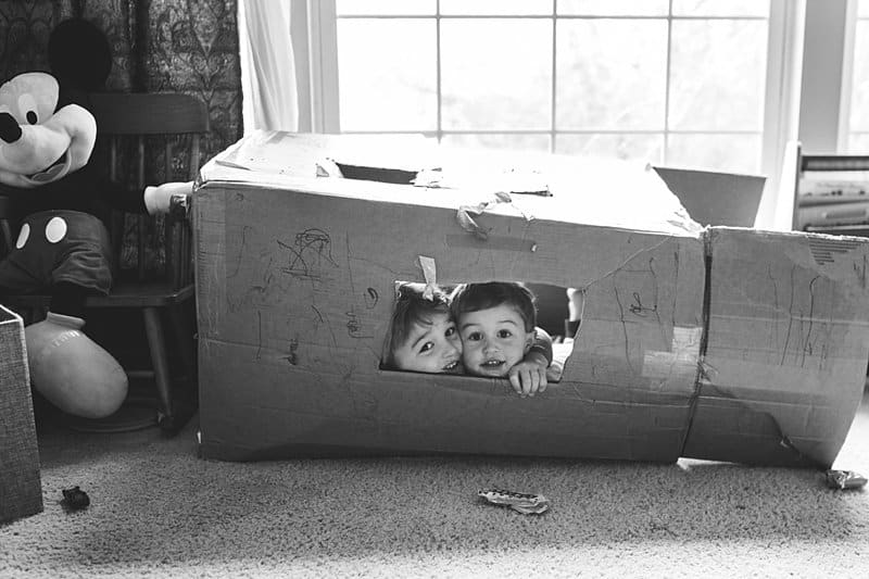 brothers in a cardboard box playhouse