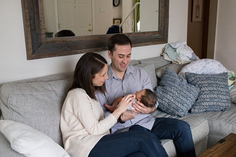 brand new baby with mom and dad on couch for lifestyle photo session in pittsburgh home