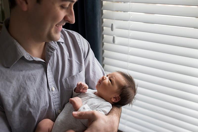 new pittsburgh dad looking at newborn by living room window