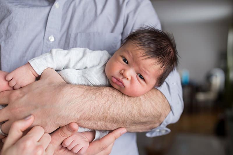 newborn boy in dads arms for baby photo session