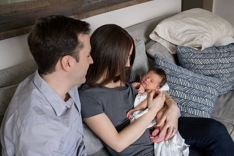 parents holding newborn on couch in pittsburgh home Sewickley newborn photographer