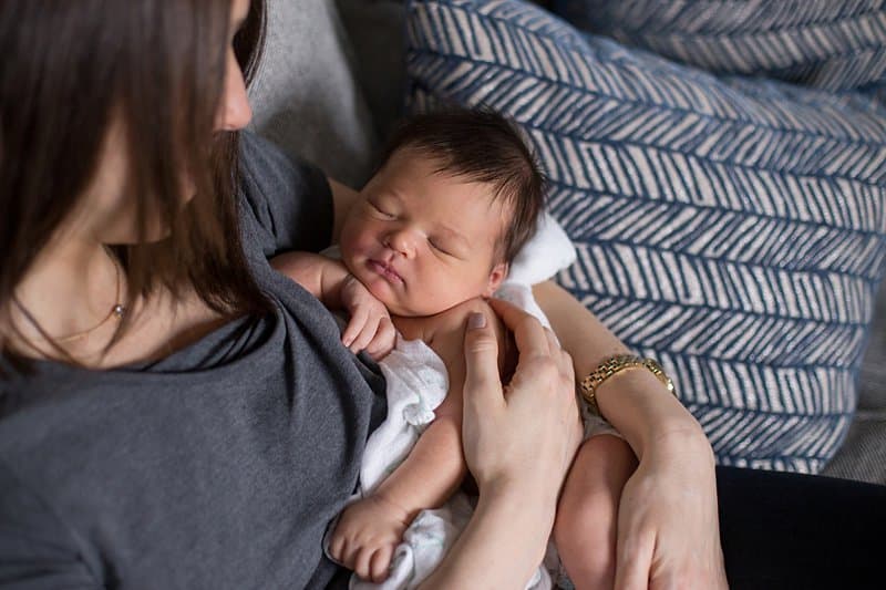 mom holding newborn on couch in pittsburgh home Sewickley newborn photographer