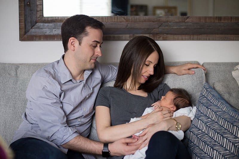 parents holding newborn on couch in pittsburgh home Sewickley newborn photographer