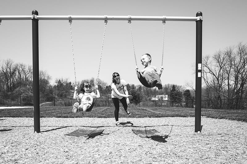 mom pushing kids on swings at mccandless area playground