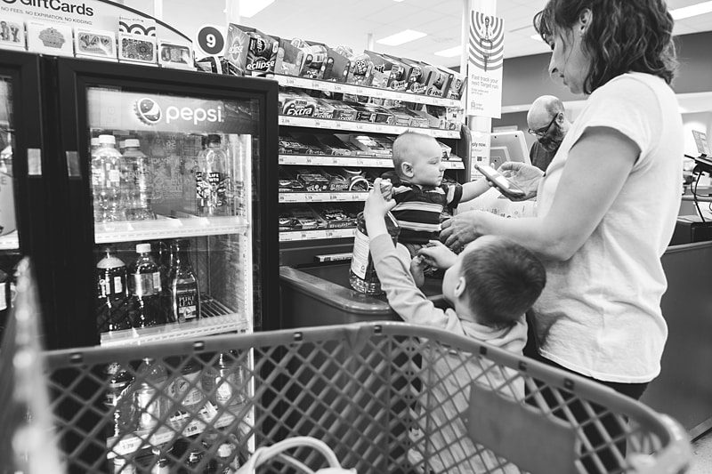 baby on checkout belt in line at target with mom and brother 