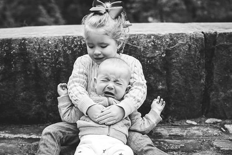 sister holding her crying brother 