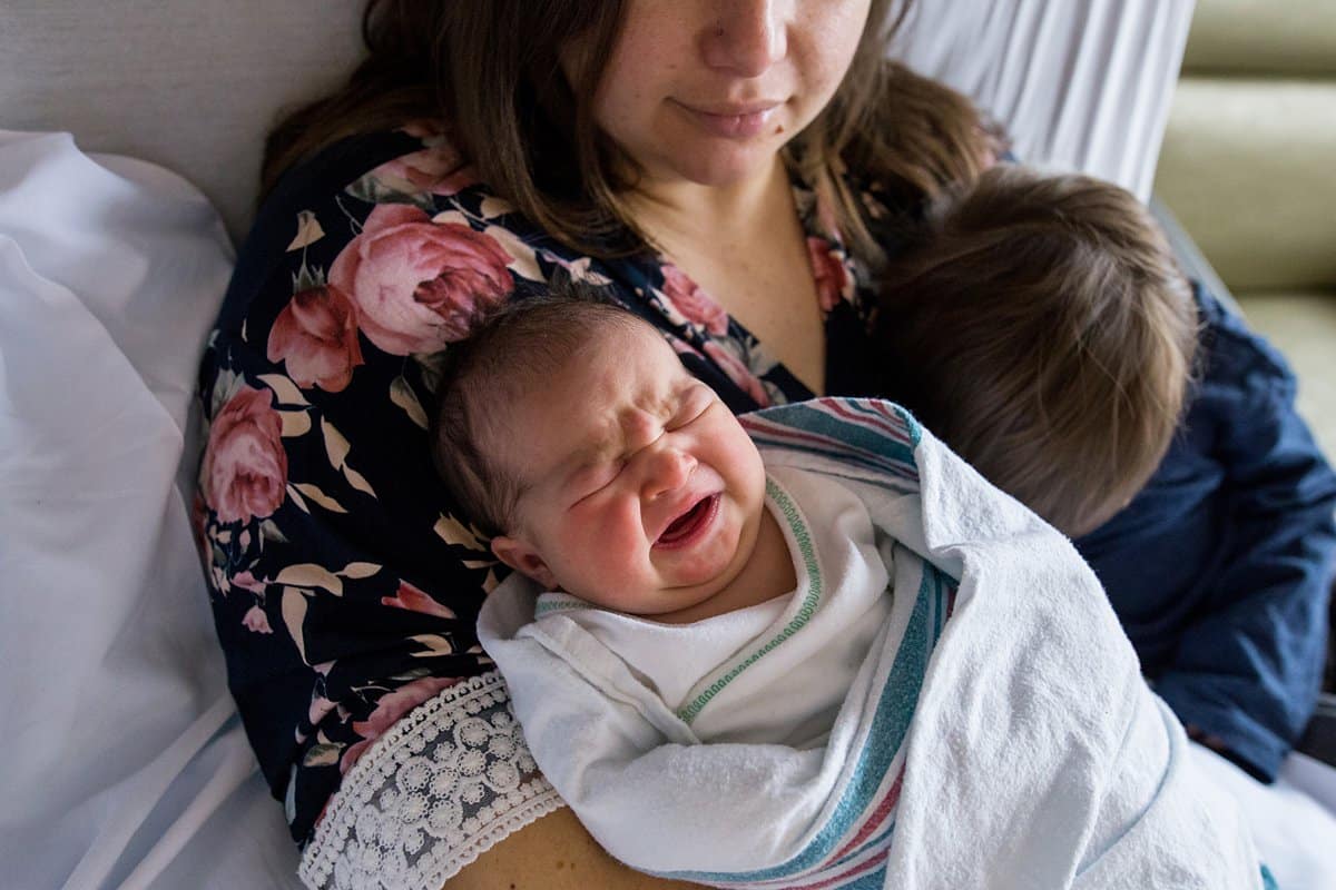 mom holding newborn baby in hospital room