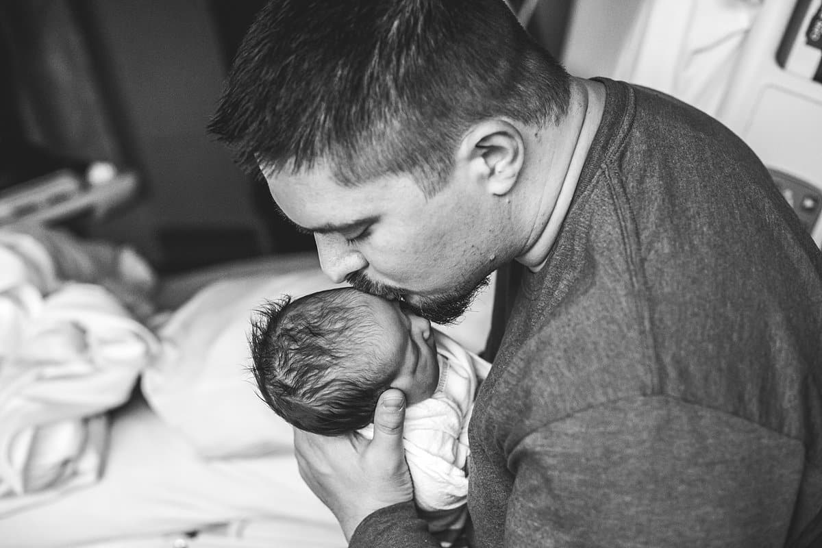 dad holding newborn baby in hospital room