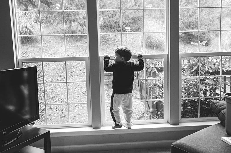little boy climbing in living room window