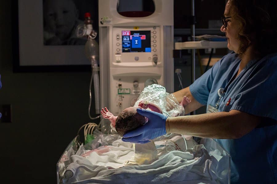 nurse at west penn holding up newborn baby