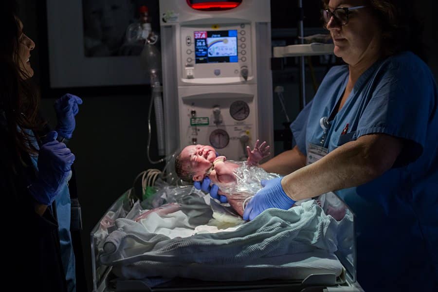nurse at west penn holding up newborn baby