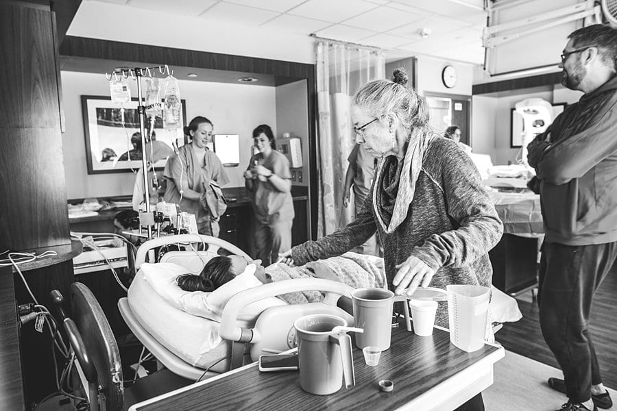 grandmother gives mother a drink during labor at hospital