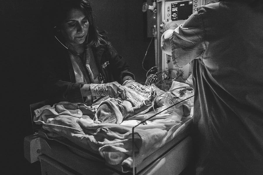 nurse looks over newborn baby at hospital