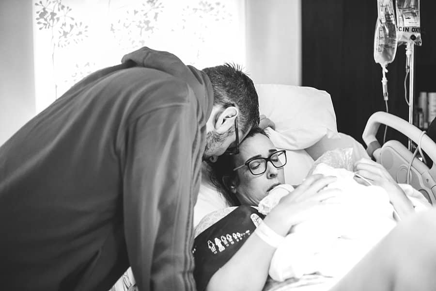 father and mother looking at baby after birth at hospital 