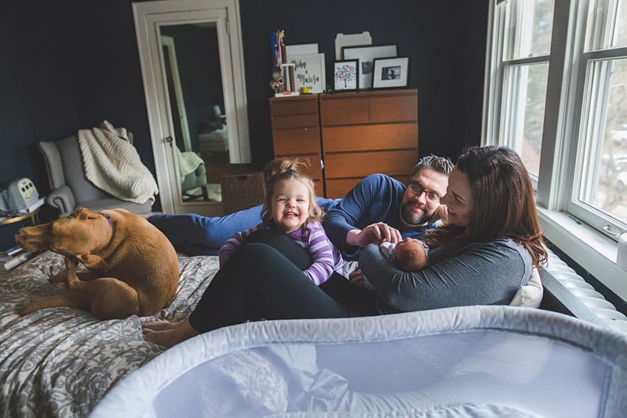 pittsburgh mom dad toddler big sister and newborn baby on bed in home 