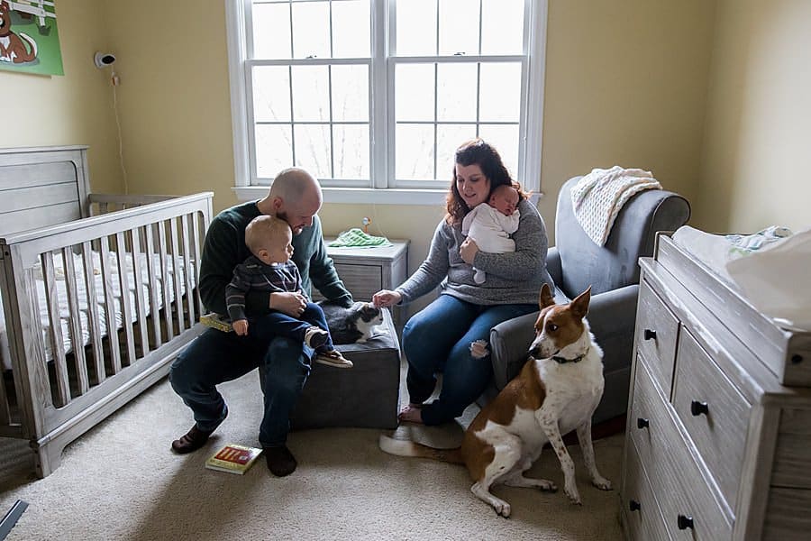 family sitting in baby nursery in pittsburgh home with dog preparing for a newborn photo session at your home!