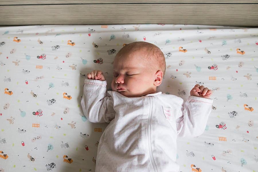 newborn baby in crib in pittsburgh home nursery