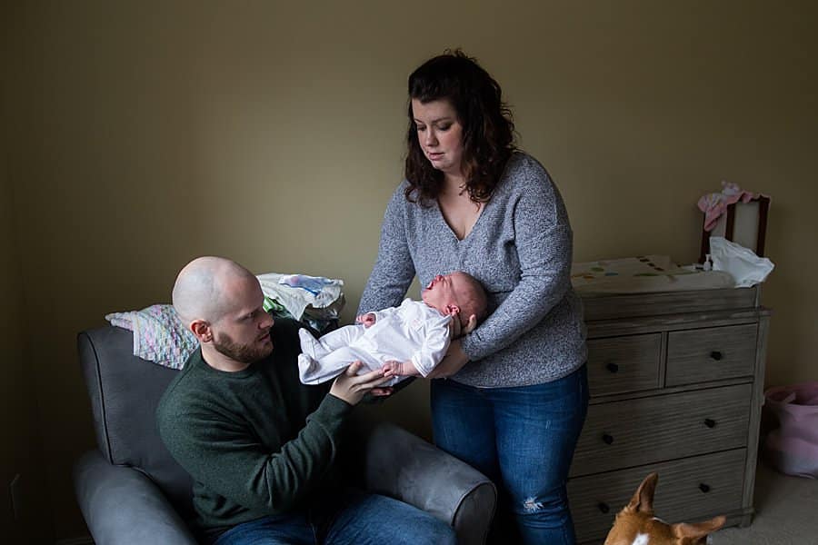 father hands newborn baby over to mother