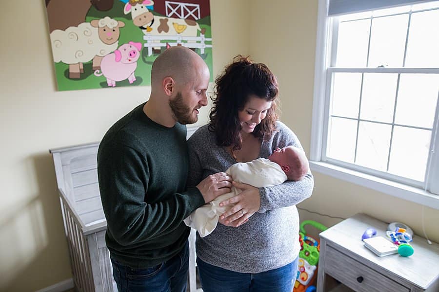 mom and dad with newborn in baby nursery in pittsburgh home