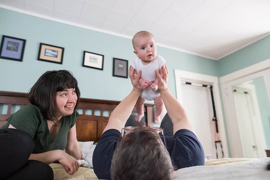 mom dad and baby on bed for lifestyle newborn photo session in pittsburgh 