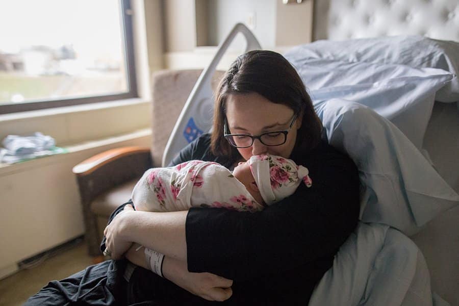 mom kissing newborn baby on hospital bed in pittsburgh for a fresh 48 session