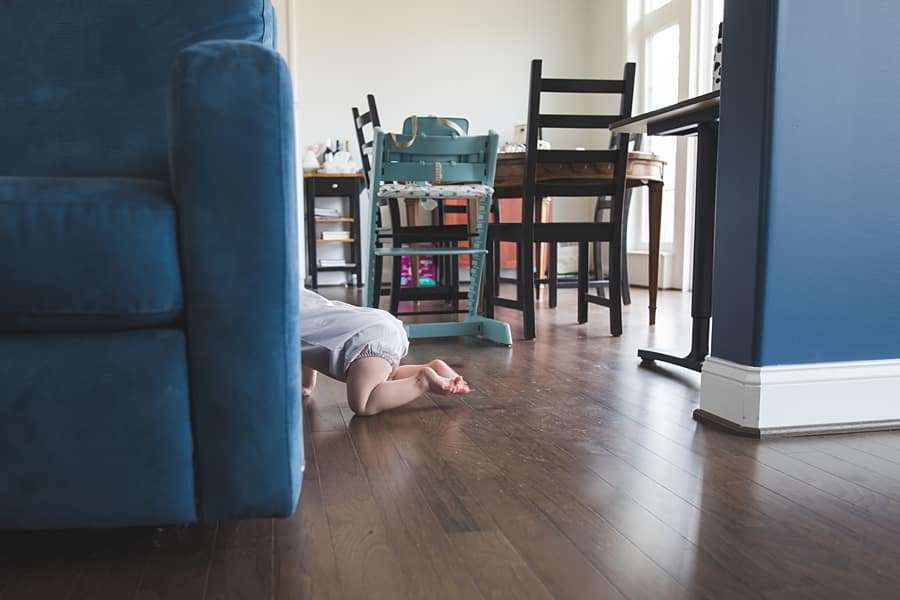 little boy crawling behind arm chair in bridgeville home for family photo session