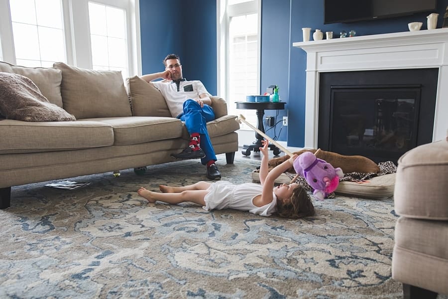 little girl on floor and dad on couch in bridgeville home for family photo session