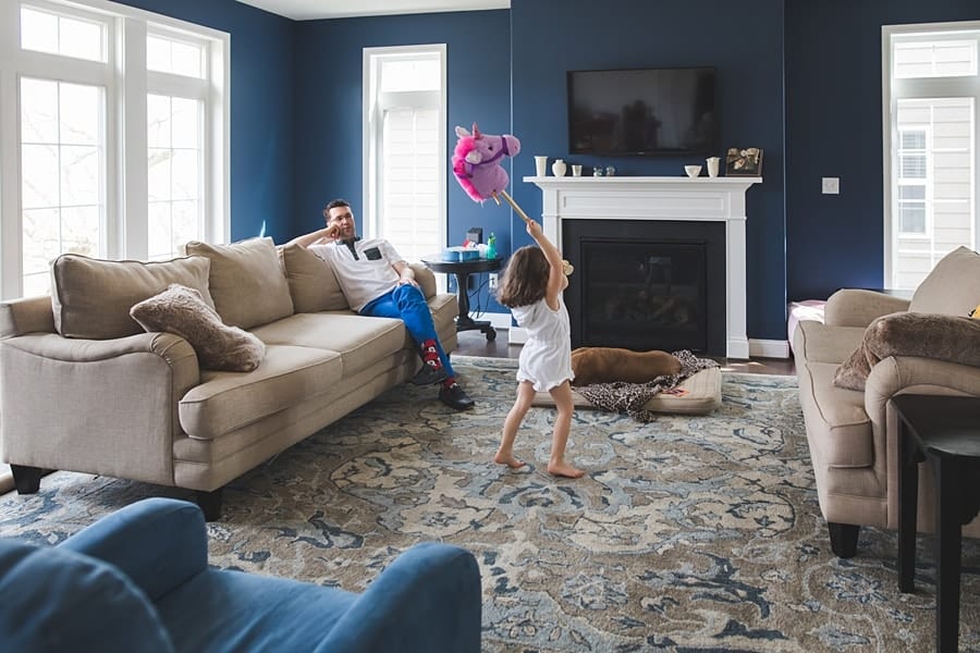 little girl dancing around and dad on couch in bridgeville home for family photo session