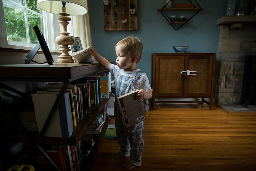 toddler taking books off shelf in pittsburgh home newborn pictures of baby Parker 