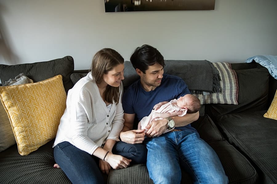 family with newborn sitting on couch of pittsburgh home for newborn photo session