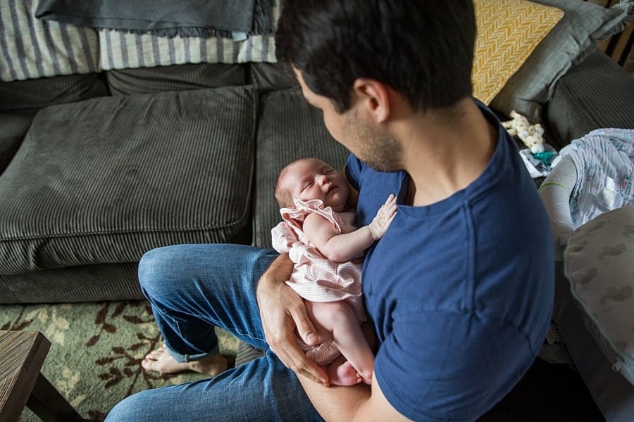 dad with newborn sitting on couch of pittsburgh home for newborn photo session newborn pictures of baby Parker 